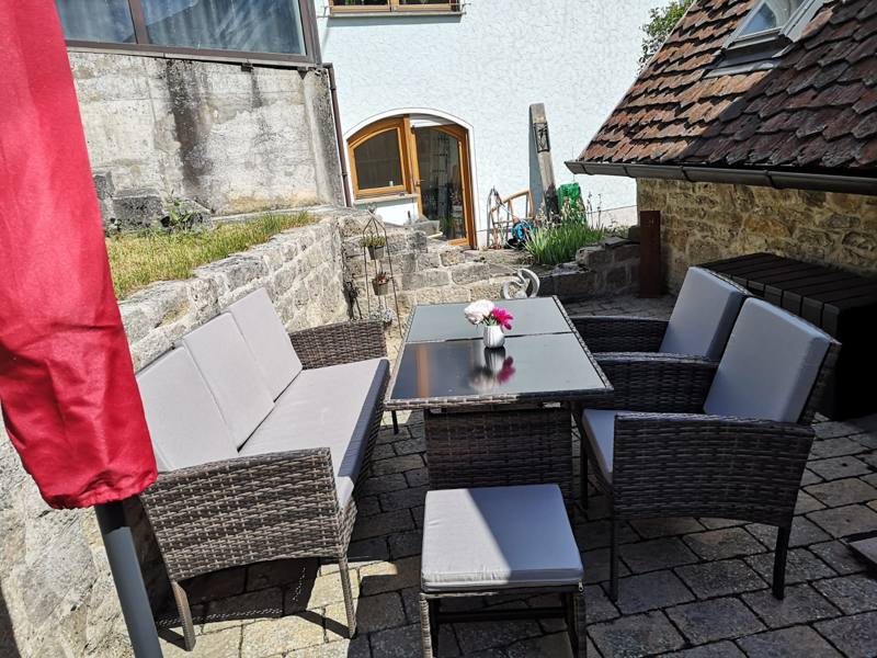 Sonnige Terrasse mit Lounge-Möbeln und Sonnenschirm