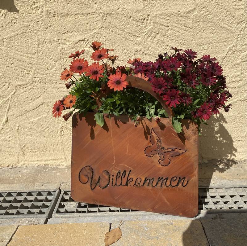 Willkommensschild mit Blumen am Eingang